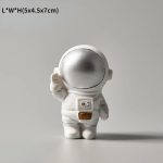 Oggetto scientifico decorativo a forma di astronauta con casco argentato e dettagli bianchi, ideale come decorazione per appassionati di scienza e spazio.