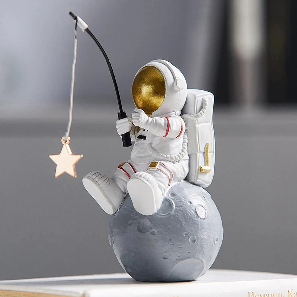Vita da astronauta con stella e luna decorativa Figurina di astronauta in tuta spaziale seduto su una luna, che tiene una canna da pesca con una stella appesa, decorazione scientifica originale e fantasiosa.