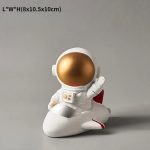 Decorazione a forma di astronauta in stile cartone animato, con casco dorato e tuta bianca, perfetta come oggetto decorativo o regalo a tema spaziale.