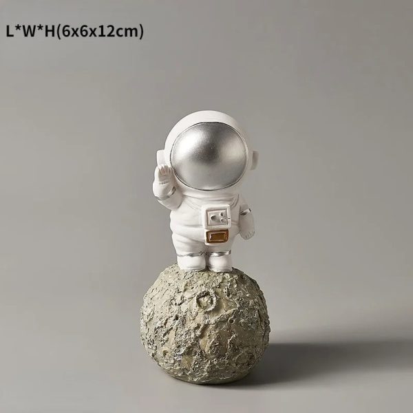 Vaso decorativo a forma di astronauta che saluta, posizionato su una superficie che ricorda la luna, perfetto come oggetto decorativo scientifico o da collezione.