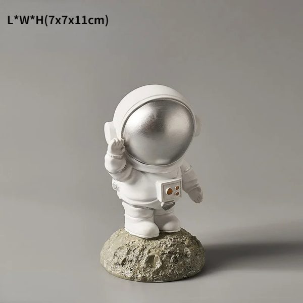 Statua di un astronauta in miniatura con casco argentato, posato su una roccia, perfetta come decorazione scientifica o da collezione.
