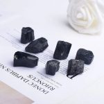Set di minerali di grafite nera naturale disposti su una pagina di testo, ideale come decorazione scientifica o oggetto da collezione. Perfetti per appassionati di scienza e decorazioni originali.