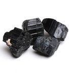 Quattro cristalli di tourmalino nero con superficie lucida e strutture a strati, ideali come decorazioni scientifiche o oggetti da collezione.