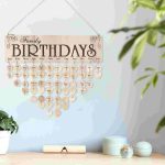 Decorazione di compleanno familiare con un calendario di cuori in legno personalizzati con i nomi e le date di nascita, appesa a una parete con piante e oggetti decorativi.