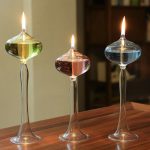 Vasi di vetro con liquidi colorati e fiamme accese, utilizzati come decorazioni scientifiche o oggetti da collezione, su una superficie di legno.