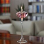 Vaso di cristallo con candela galleggiante e liquido rosa, decorazione scientifica elegante per ambienti moderni.