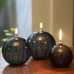 Tre palline di vetro con fiamme accese, ideali come decorazioni scientifiche o oggetti di design innovativi, perfetti per ambienti moderni e creativi.