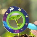 Piantina di pianta in lente scientifica con decorazioni spaziali, simbolo di esplorazione e scoperta scientifica, ideale come decorazione educativa o regalo per appassionati di scienza.