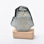 Pietra decorativa in vetro con simboli scientifici dorati, su base di legno, oggetto decorativo per appassionati di scienza e design innovativo.