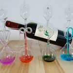 Vasi da laboratorio con liquidi colorati e bottiglia di vino, decorazioni scientifiche per ambienti educativi e di design.