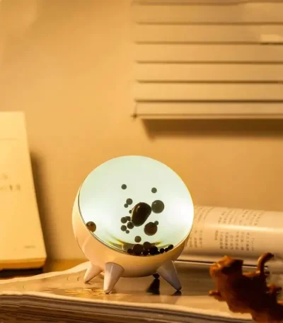Oggetto decorativo scientifico con superficie luminosa e bolle nere, ideale per ambienti educativi o come pezzo di design ispirato alla scienza.