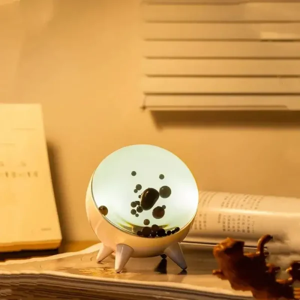 Oggetto decorativo scientifico con superficie luminosa e bolle nere, ideale per ambienti educativi o come pezzo di design ispirato alla scienza.