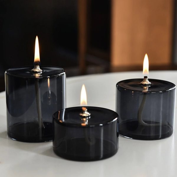 Tre candele scientifiche in vetro nero con fiamme accese, create per decorazioni e ambienti eleganti, ispirate al mondo della scienza.