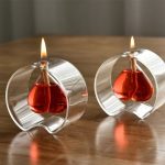 Due vasetti di cera con fiammella accesa, decorativi e scientifici, ideali per ambienti studiati e decorazioni a tema scientifico.