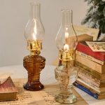 Lampada a olio vintage con vetro trasparente e base in vetro color ambra, perfetta come decorazione storica o oggetto da collezione.
