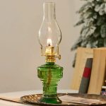 Lampada a olio vintage in vetro verde con fiamma accesa, decorativa e funzionale.