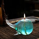 Palla di vetro a forma di balena con candela accesa, decorazione scientifica e artistica in vetro trasparente e blu.