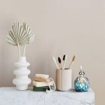 Spazzolino da denti in bambù e decorazioni naturali in ceramica e vetro, ideale per un bagno ecologico e decorativo.