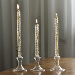 Tre candele accese su supporti di vetro decorativi, creando un'atmosfera calda e raffinata. Perfette come decorazioni scientifiche o per ambienti eleganti.