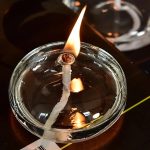 Candela scientifica accesa in un contenitore di vetro, con fiamma alta e fumo visibile, ideale per decorazioni e dimostrazioni scientifiche.