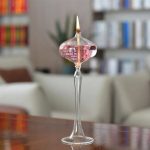Vaso di cristallo con candela accesa e liquido rosa, decorazione scientifica elegante.