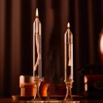 Due candele di laboratorio in vetro con fiamma accesa, ideali come decorazioni scientifiche o per esperimenti. Design elegante e trasparente, perfette per ambienti educativi o decorativi.