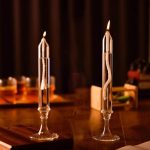 Due candele scientifiche in vetro con fiamme accese, ideali come decorazioni per ambienti a tema scientifico o educativi. Perfette per creare un'atmosfera suggestiva e stimolante.