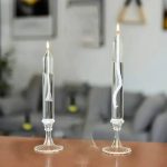 Due vetri di esperimenti scientifici con candele accese, che mostrano il principio della capillarità e della combustione in un ambiente di laboratorio o decorativo.