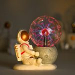 Figura di un astronauta in miniatura accanto a una sfera di plasma luminosa, simbolo di esplorazione spaziale e scienza.