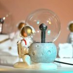 Vaso decorativo con lampadina e astronauta in miniatura, perfetto come oggetto scientifico e decorativo per appassionati di spazio e tecnologia.