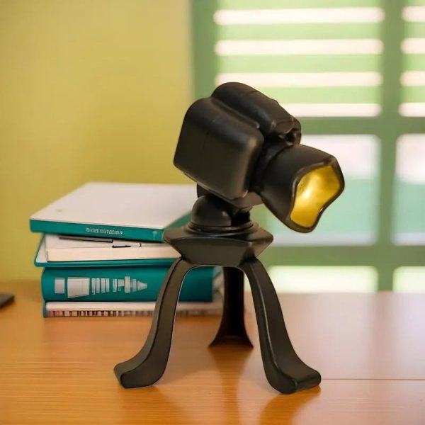Microscopio da tavolo con supporto nero, ideale per studi scientifici e osservazioni dettagliate, posizionato su un tavolo con libri e sfondo luminoso.