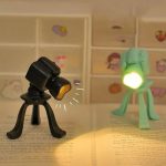 Lampada scientifica in miniatura con luce LED verde e corpo nero, perfetta come decorazione educativa o regalo a tema scienza.