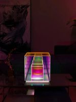 Piramide di vetro trasparente illuminata con luci LED multicolore, posizionata su un tavolo in un ambiente moderno e artistico.