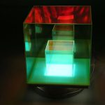 Oggetto decorativo in vetro con illuminazione LED multicolore, perfetto come decorazione scientifica o elemento di design moderno.