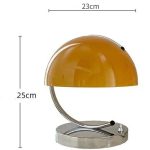 Lampada da tavolo con paralume arancione e base in metallo, perfetta per ambienti di studio o decorazioni scientifiche.