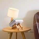 Lampada da tavolo con base in legno e libri decorativi posizionati come supporto, ideale per ambienti di studio o soggiorno con stile scientifico.