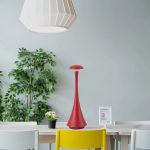 Lampada decorativa scientifica rossa in ambiente moderno con piante e sedie colorate.