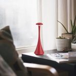 Pezzo decorativo ispirato alla scienza, in forma di oggetto elegante e moderno, posizionato su un tavolo vicino a una finestra con piante e riviste.