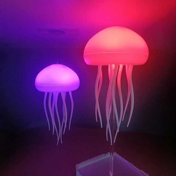 Due lampade a forma di meduse con luci LED rosa e viola, create per decorazioni scientifiche e ambienti moderni, con tentacoli ondulati e luce soffusa.