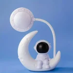 Oggetto decorativo a forma di astronauta seduto sulla luna con lampada a forma di pianeta, ideale come decorazione scientifica e oggetto da collezione.