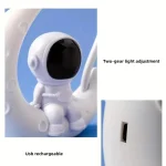 Piccolo robot astronauta bianco con testa nera, dotato di luce regolabile a due velocità e porta di ricarica USB, ideale come decorazione scientifica o oggetto da collezione.