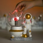 Vaso di Tesla con effetto di scariche elettriche e figura di astronauta decorativa, perfetto come oggetto scientifico e decorativo per appassionati di scienza e spazio.