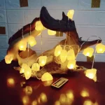 Luci decorative a forma di pietre luminose posizionate su un tronco di legno naturale, creando un'atmosfera calda e accogliente. Perfette per decorazioni di ambienti interni o esterni con stile natura.