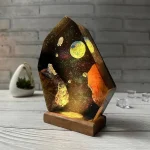 Oggetto decorativo ispirato allo spazio con effetto galassia, pianeti e stelle, inserito in una base di legno, perfetto come decorazione scientifica o da collezione.