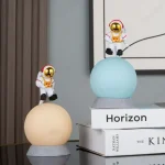Decorazioni spaziali con astronauti in miniatura su sfere luminose, ideali per arredamento a tema scientifico o per appassionati di spazio e astronomia.