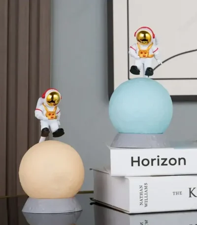 Decorazioni spaziali con astronauti in miniatura su sfere luminose, ideali per arredamento a tema scientifico o per appassionati di spazio e astronomia.
