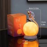 Lampada decorativa a forma di astronauta sulla luna, perfetta come luce notturna o decorazione scientifica, con dimensioni di 15cm di altezza e 8cm di diametro.