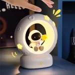 Lampada notturna a forma di astronauta sulla luna con luci soffuse e dettagli colorati, ideale come decorazione per camerette e appassionati di spazio.