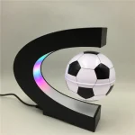 Lampada decorativa a forma di pallone da calcio con base a mezzaluna nera e luce LED colorata, ideale come oggetto di decorazione sportiva e per ambienti moderni.