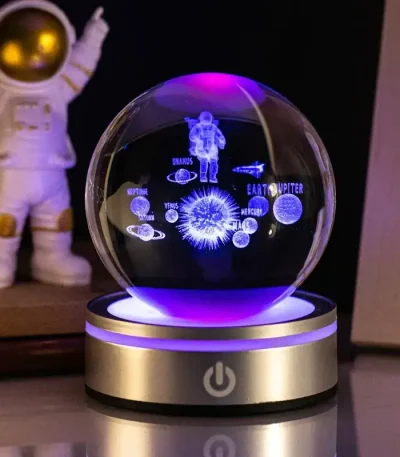 Palla di cristallo con rappresentazioni luminose di pianeti e astronauta, ideale come decorazione scientifica o oggetto da collezione.